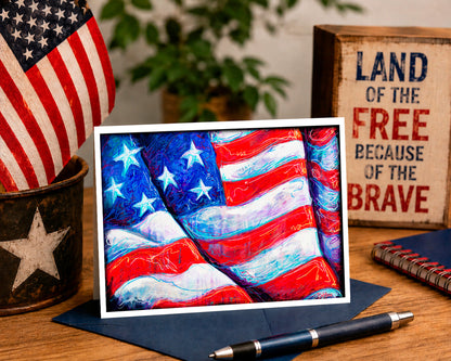Colorful American flag painting on a wooden table with an American flag, plant, and 'Land of the Free Because of the Brave' sign in the background.